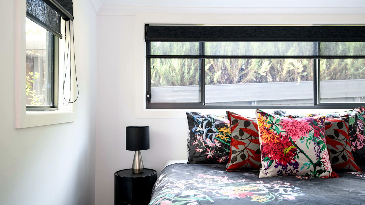 A bedroom with a bed, a nightstand, a lamp, and a window with a view of trees.