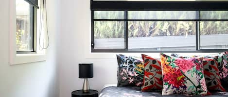A bedroom with a bed, a nightstand, a lamp, and a window with a view of trees.