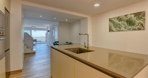A modern kitchen with a central island, a dining area with chairs, and a staircase leading to an upper level. - Spacious apartment for 6 with terrace and WiFi · Llafranc (Llafranc)