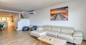 A modern living room with a beige sofa, a wooden coffee table, and a painting of a sunset over a beach. - Spacious apartment for 6 with terrace and WiFi · Llafranc (Llafranc)
