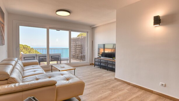 A modern living room with a sofa, a coffee table, a TV, and a balcony with a view. - Spacious apartment for 6 with terrace and WiFi · Llafranc (Llafranc)