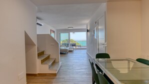 A modern interior with a staircase leading to a balcony, a dining area with a glass table, and a view of the sea. - Spacious apartment for 6 with terrace and WiFi · Llafranc (Llafranc)