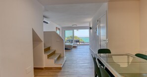 A modern interior with a staircase leading to a balcony, a dining area with a glass table, and a view of the sea. - Spacious apartment for 6 with terrace and WiFi · Llafranc (Llafranc)