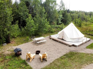 A tented area with a picnic table, chairs, and a fire pit.