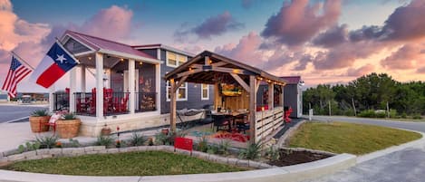 A building with a covered porch, outdoor seating, and American flags.