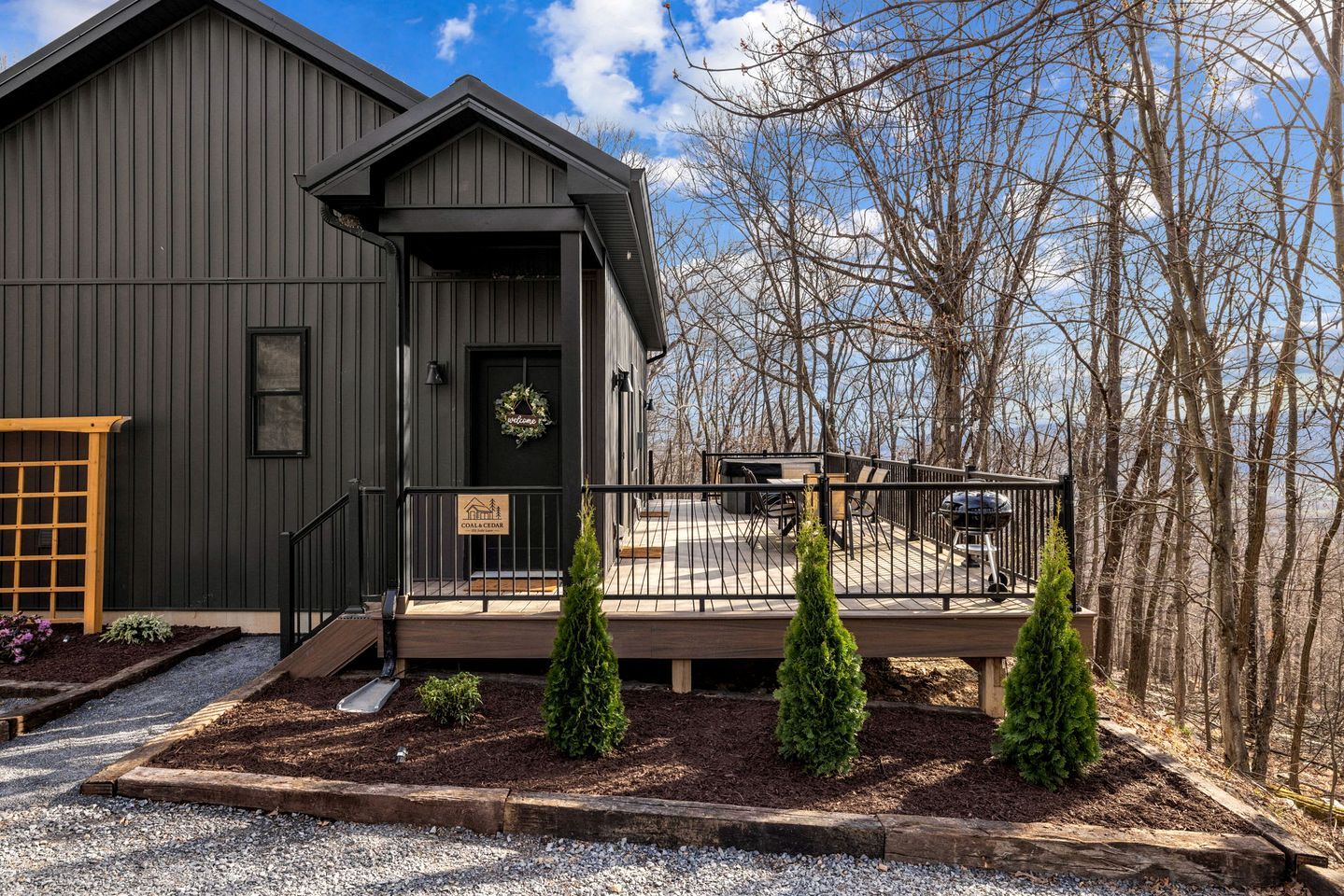 A dark-colored building with a porch, a welcome sign, and a sign indicating a lodge.