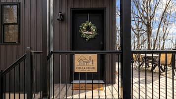 A wooden building with a black door, a welcome sign, and a signboard for 'COAL & CEDAR' at 252 Judy Lane.