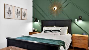 A bedroom with a bed, bedside tables, a nightstand, a bench, and wall-mounted artwork.