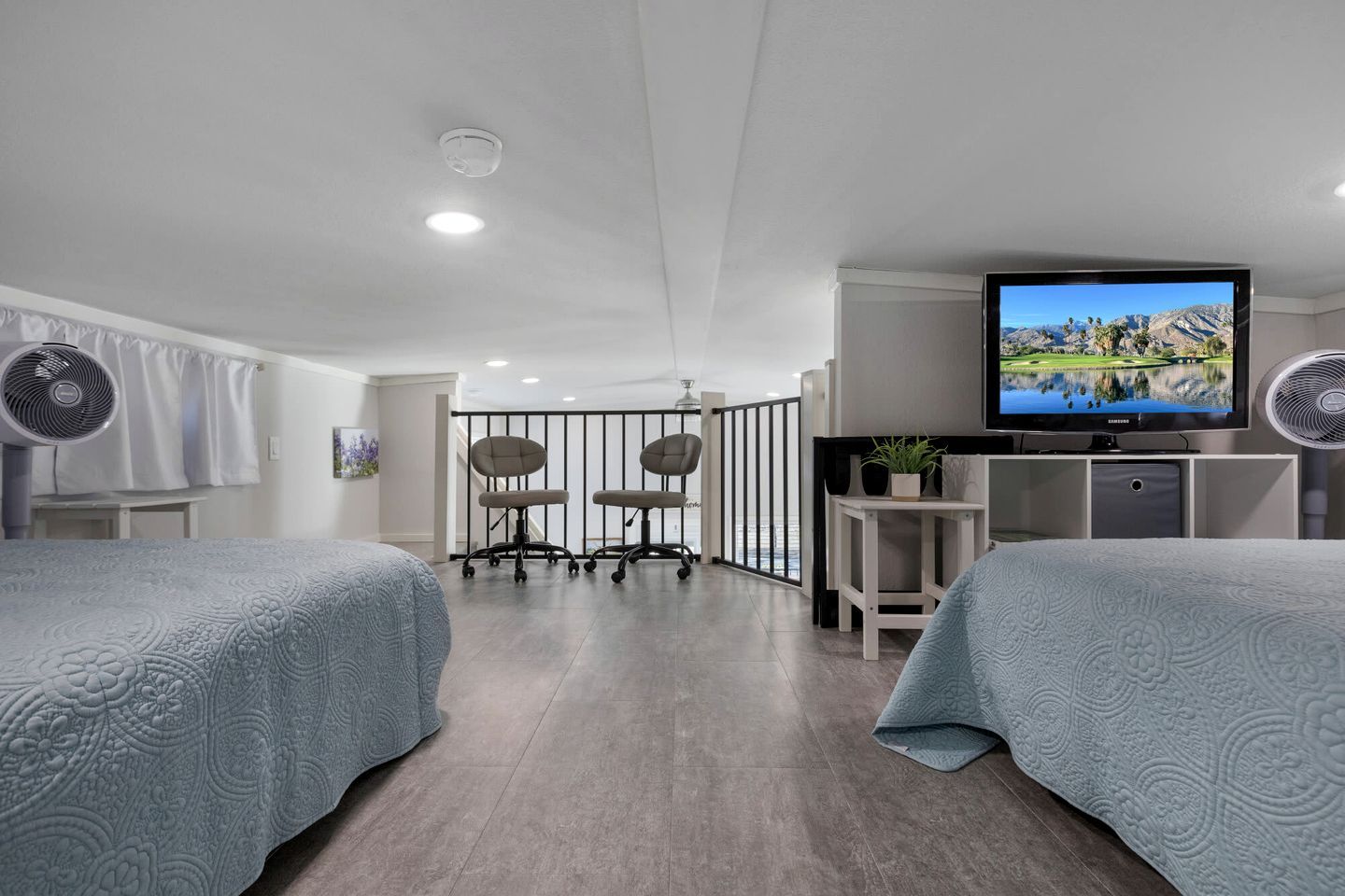 Habitación de hotel con dos camas, un escritorio, televisión y balcón con vistas.
