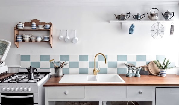 A kitchen with a gas stove, white sink, and a wooden countertop.