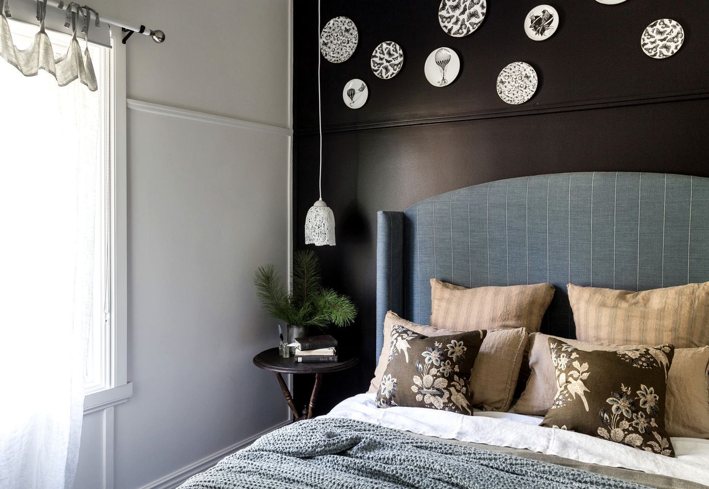 A bedroom with a bed, a nightstand, a potted plant, and wall decor.