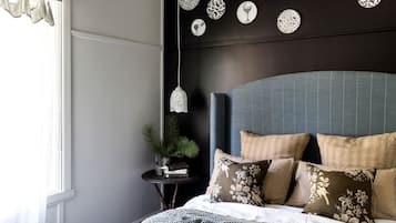 A bedroom with a bed, a nightstand, a potted plant, and wall decor.