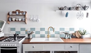 A kitchen with a gas stove, white sink, and a wooden countertop. - Cute Wooden Cabin with Fireplace in Daylesford, Victoria (Daylesford)
