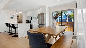 Una cocina moderna con armarios blancos, una mesa de comedor de madera y taburetes de bar.
