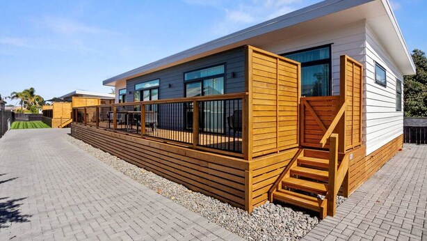 Un edificio moderno con una terraza de madera, una escalera y un sendero pavimentado.
