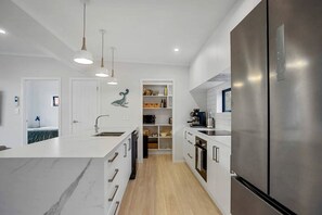 A modern kitchen with white cabinetry, a central island, a stainless steel refrigerator, and pendant lighting.