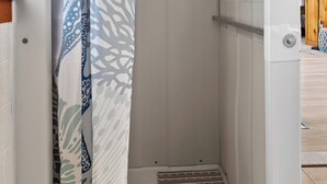 Suihkutilassa on kuviollinen suihkuverho, metallinen suihkun säätöventtiili ja puinen katto.