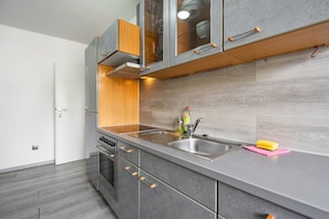 Une cuisine moderne avec des meubles gris, un évier en acier inoxydable et un plan de travail en bois.