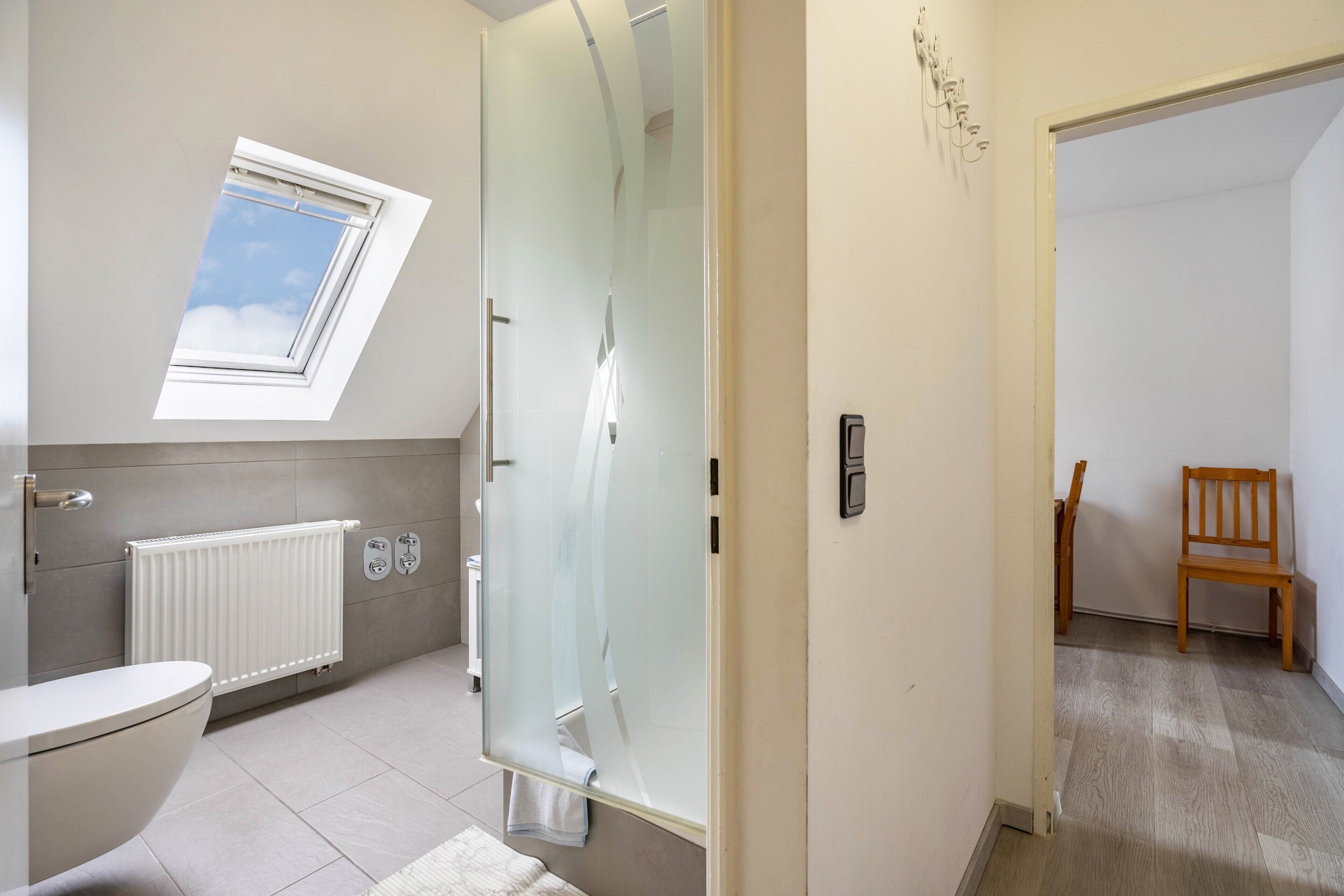 Ein modernes Badezimmer mit Oberlicht, Duschkabine und Toilette.