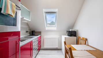 Une cuisine de taille réduite aux couleurs rouge et blanche, avec une petite fenêtre et une vue sur le ciel.
