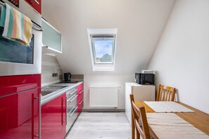 Une cuisine de taille réduite aux couleurs rouge et blanche, avec une petite fenêtre et une vue sur le ciel.