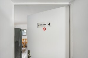 Una puerta con un letrero que indica 'APARTMENT 4' y un símbolo de prohibido fumar.