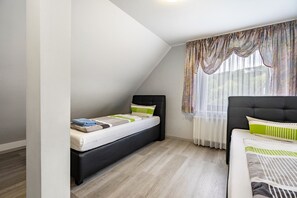 Un dormitorio con una cama, una cama individual y una ventana con cortinas.