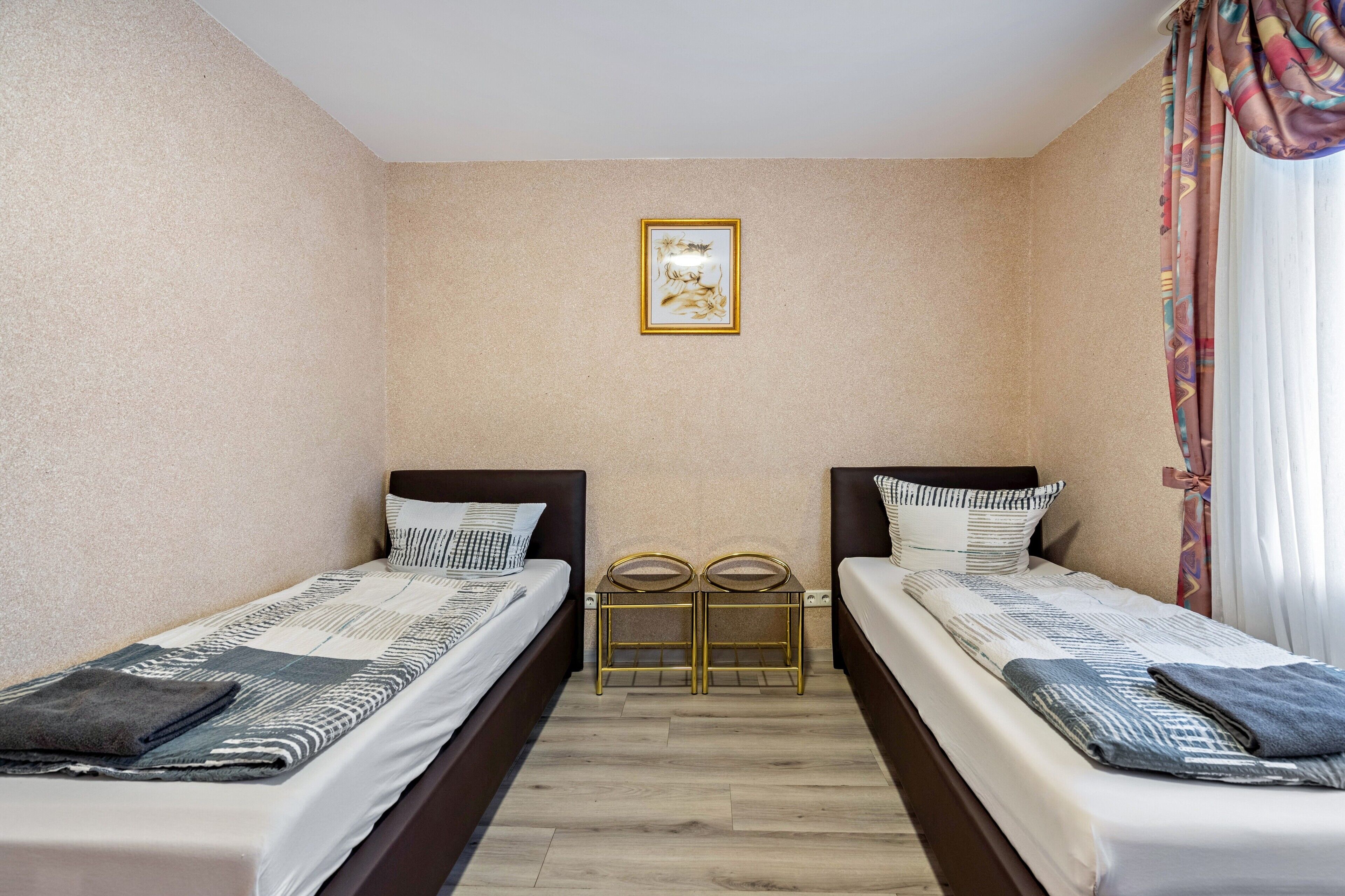 Ein Hotelzimmer mit zwei Einzelbetten, einem kleinen Tisch und einem an der Wand hängenden Bild.