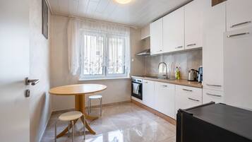 Una cocina compacta con comedor, que incluye una mesa y dos taburetes, una estufa y un refrigerador.