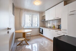 Una cocina compacta con comedor, que incluye una mesa y dos taburetes, una estufa y un refrigerador.