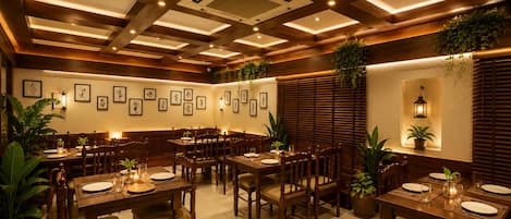 Un restaurante con mesas y sillas de madera, luces empotradas en el techo y cuadros colgados en las paredes.