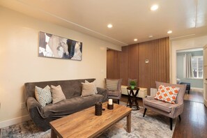 A modern living room with a sofa, armchair, coffee table, and a painting on the wall. - Chula Vista Duplex Near Gaylord Pacific Sleeps 12! (Chula Vista)