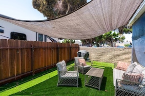 A backyard with a wooden fence, a barbecue grill, and outdoor furniture. - Chula Vista Duplex Near Gaylord Pacific Sleeps 12! (Chula Vista)
