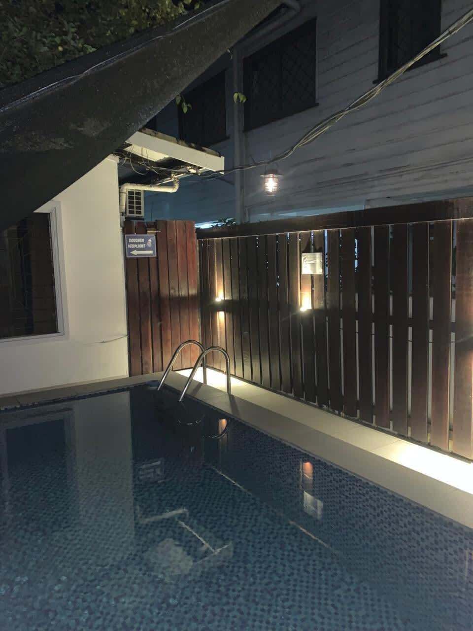 Una piscina con cerramiento de madera, una escalera e indicación de zona permitida para perros.