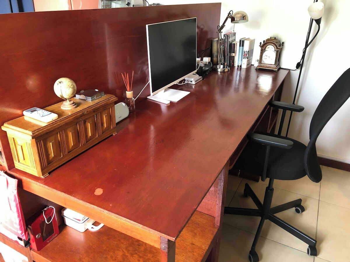 A wooden desk with a computer, a lamp, and various office supplies.