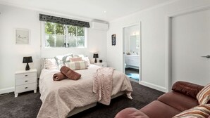 Un dormitorio con cama, mesitas de noche, un espejo y una puerta.