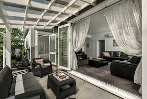 Ein modernes Wohnzimmer mit Glaswand, einer schwarzen Ledersofa und einem Essbereich mit Tisch und Stühlen.