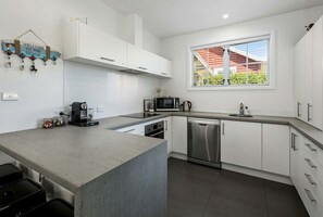 A modern kitchen with white cabinets, a stainless steel dishwasher, and a built-in oven.