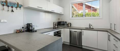 A modern kitchen with white cabinets, a stainless steel dishwasher, and a built-in oven.