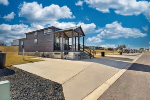 A modern building with a covered outdoor area, a concrete pathway, and a clear sky. - Upscale and Relaxing Tiny Home Getaway with Resort Amenities and Pool Near Fredericksburg, TX (Fredericksburg)
