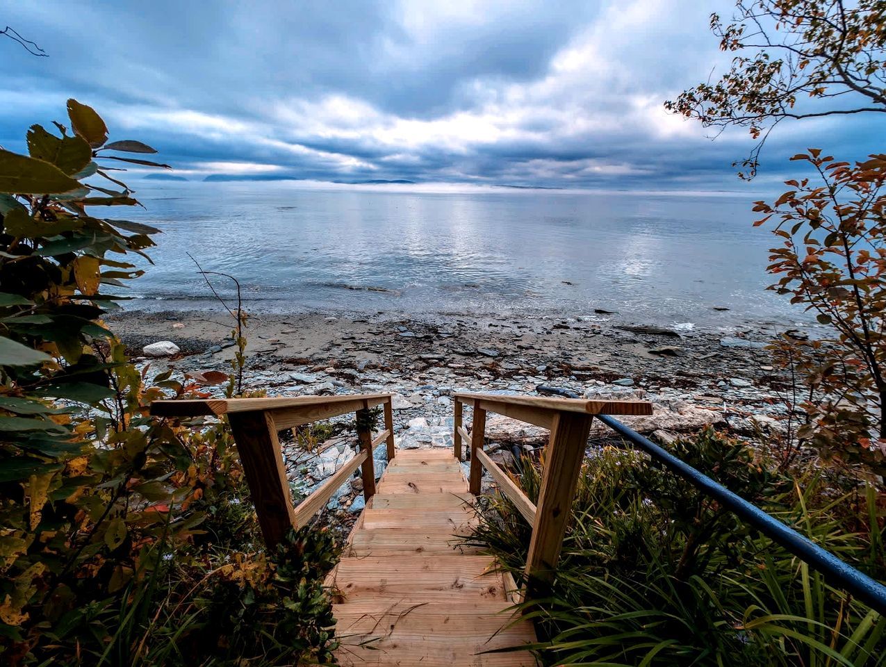 Un sentier en bois mène à une plage, et une rambarde est installée sur un de ses côtés.