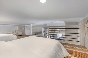 Ein Hotelzimmer mit zwei Betten, einem Balkon mit Geländer und Blick zur Küche.