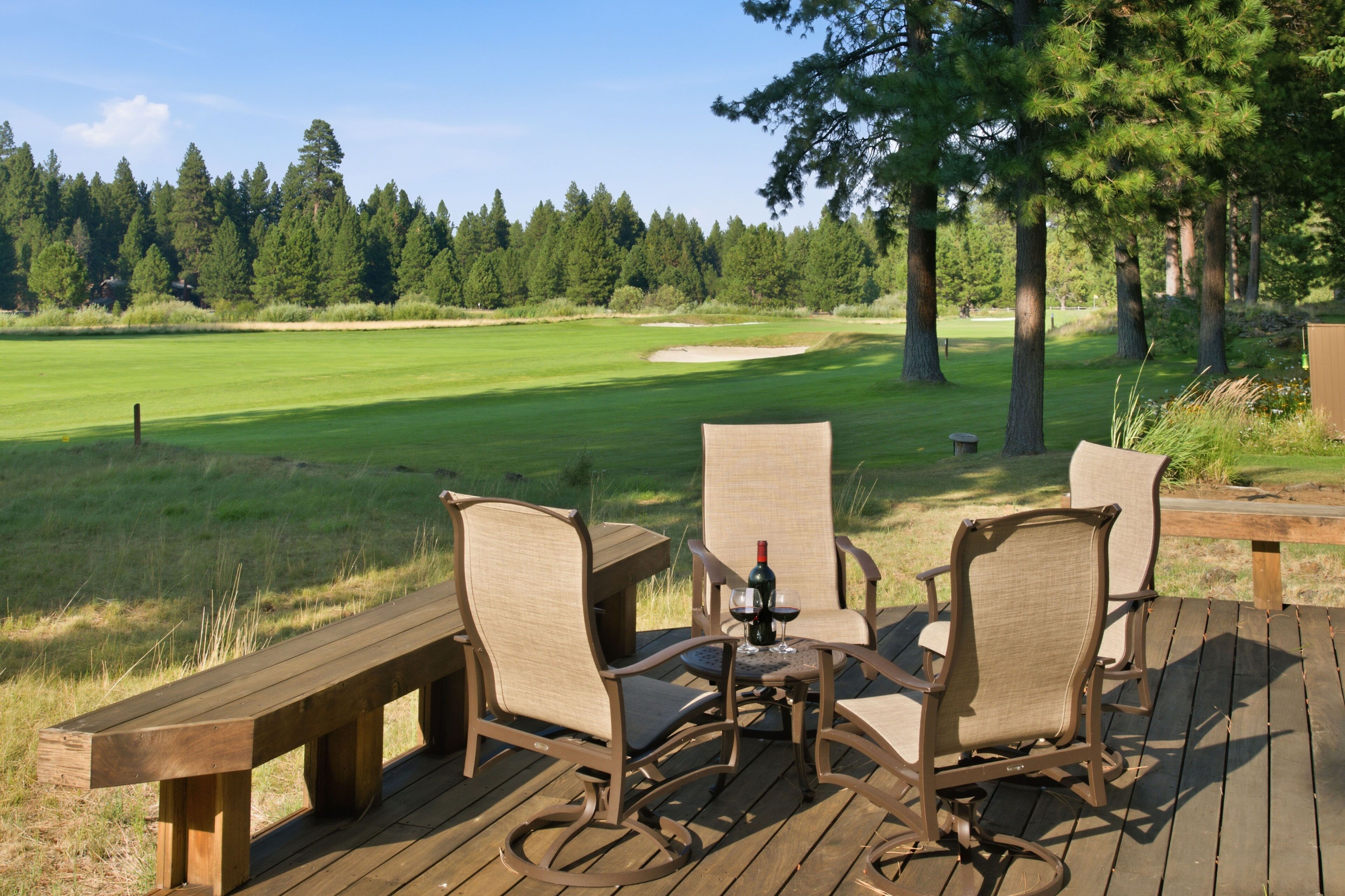 A deck with outdoor furniture overlooking a golf course.