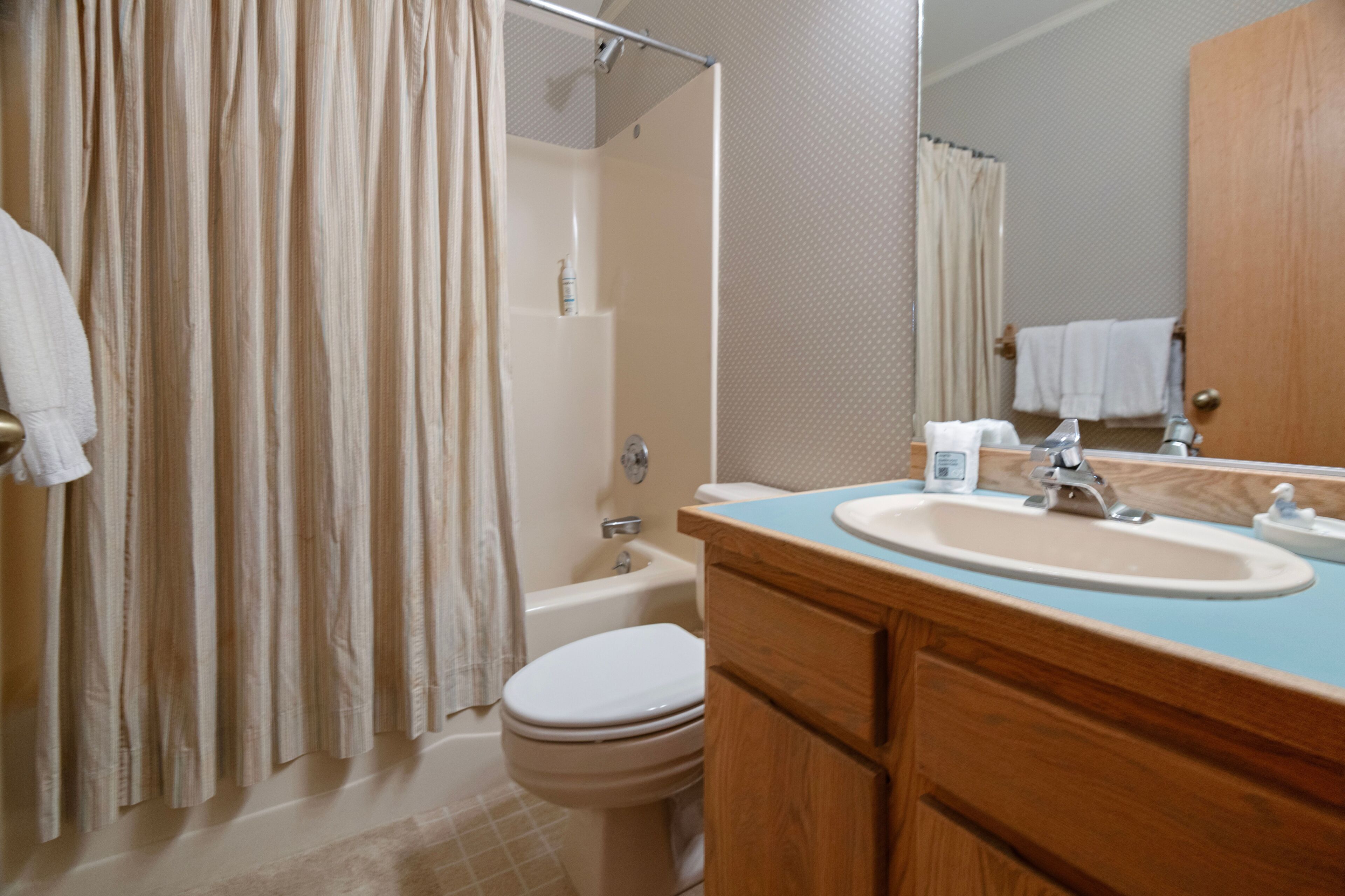 A bathroom with a bathtub, toilet, sink, and a mirror.