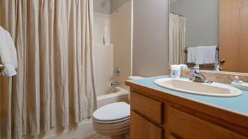 A bathroom with a bathtub, toilet, sink, and a mirror.