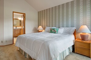 A bedroom with a large bed, two bedside lamps, a nightstand, and a door leading to a bathroom. - Relax with Mountain and BBR Golf Course Views (Sisters)