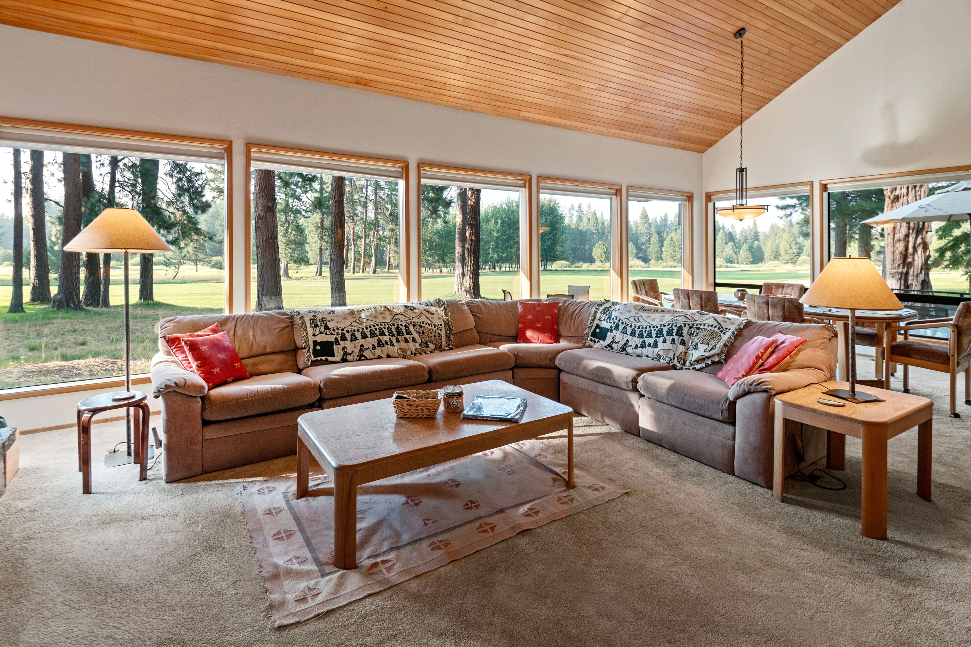 A spacious living room with a large sectional sofa, a coffee table, and a view of a golf course through large windows.
