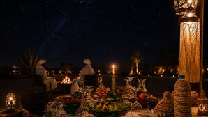 A table set for dining with a night sky view, lit candles, and traditional decor.