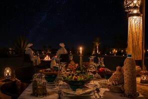 A table set for dining with a night sky view, lit candles, and traditional decor.