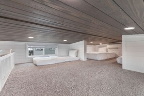 Ein Schlafzimmer mit schrägem Dach, eingebauten Stauraum und einem Fenster mit Jalousien.